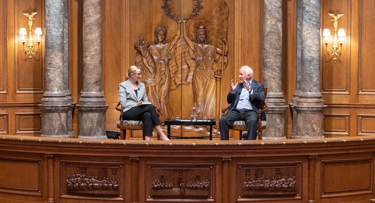 Holly Kuzmich and Jim Towey in a church have a discussion.